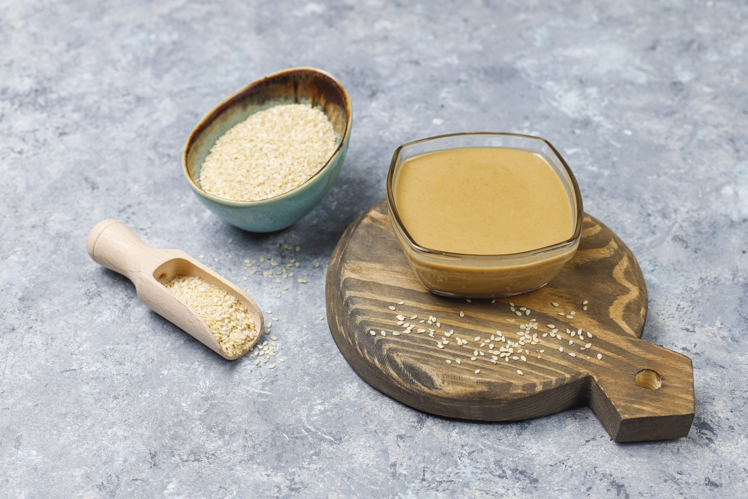 bowl of tahini with sesame seeds on concrete background