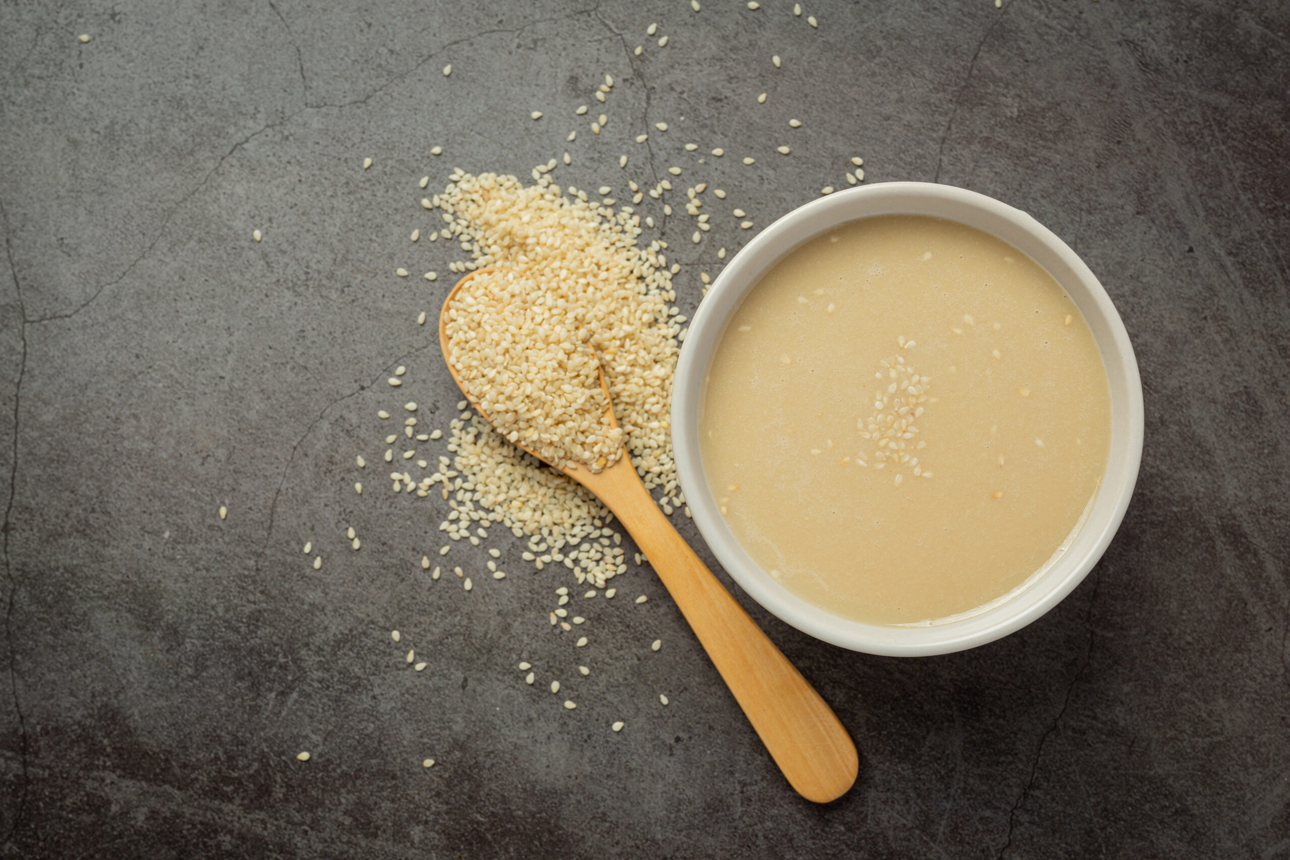 tahini et graines de sésame sur fond sombre